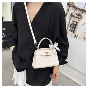 Detailed close-up of white crocodile pattern handbag with silk scarf and rotating lock
