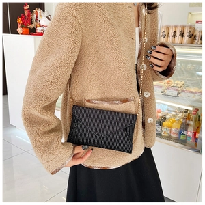 Detail view of a black envelope bag with sparkling rhinestones and a gold chain strap