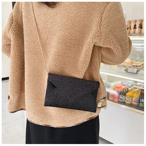 Detailed view of a black envelope crossbody bag with white dots and gold chain strap