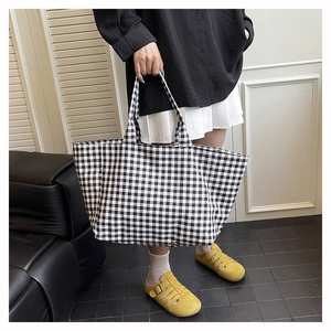 Detail of large black and white checkered canvas tote bag with yellow metallic buckle sandals