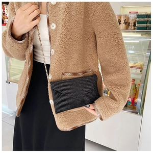 Close-up of a black rhinestone mini envelope crossbody bag with a slim gold chain strap