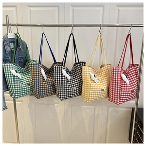 Row of plaid nylon tote bags in green, blue, black, yellow, and red with dog charms