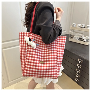 Detail showing the red and white gingham tote bag with handmade metal label and plush dog charm