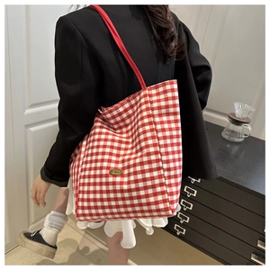 Detailed view of large red and white plaid canvas tote bag with sturdy handles on shoulder