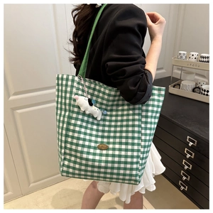 Detail showing green checkered canvas tote with a cute white puppy plush keychain