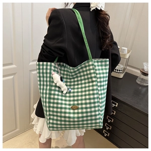 Détail du sac cabas en toile à carreaux verts et blancs avec badge métal et breloque chien