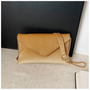 Detail of elegant gold sequined envelope evening bag with fine metallic chain strap