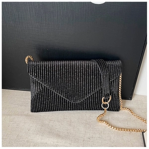Detail of black envelope clutch featuring silver rhinestones and a gold chain strap