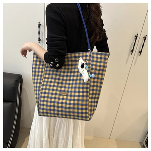 Detail of checkered canvas tote bag with blue strap and cute puppy plush pendant