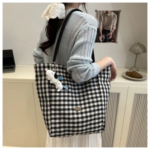Détail du sac cabas en toile à damier noir et blanc avec un joli pendentif chien blanc