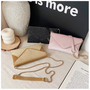 Three rhinestone envelope clutch bags in black, pink, and gold with gold chain straps