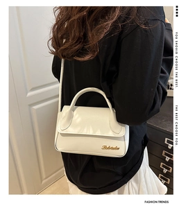 Gros plan d'un sac à main blanc avec logo doré et bandoulière réglable sur un mannequin