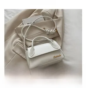Vue macro détaillée du mini sac à main blanc avec logo doré et bandoulière à nœuds