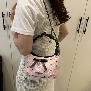 Sac à bandoulière vintage rose avec nœud en satin noir et breloque cœur sur un mannequin