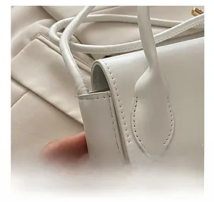 Détail du sac à main en similicuir blanc montrant les coutures et la poignée ronde