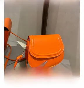 Detail of bright orange saddle bag showing fine leather texture and quality stitching