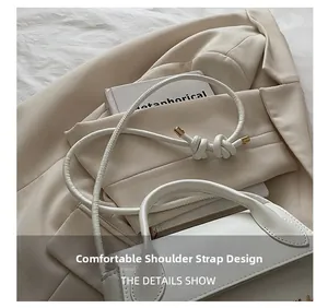Détail d'un sac à main en cuir blanc avec une bandoulière nouée unique et des garnitures dorées