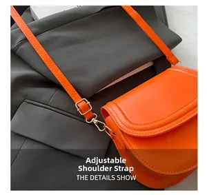 Detail showing bright orange saddle bag with adjustable strap and gold metal hardware