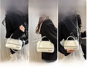 Démonstration de trois ports du sac à bandoulière en cuir blanc avec logo doré chic