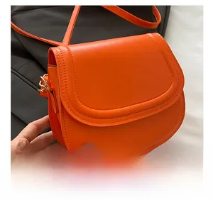 Close-up of orange leather saddle bag showing fine texture and gold metal buckle