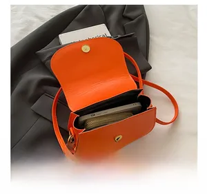 Top view of bright orange crossbody bag showing capacity for smartphone and wallet