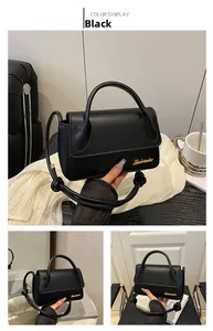 Vue détaillée du sac en cuir noir avec bandoulière nouée et logo doré élégant