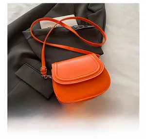 Detail showing bright orange saddle bag on grey blazer with mobile phone for scale
