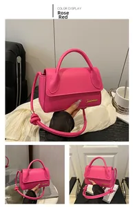 Détail du sac bandoulière en cuir rose fuchsia avec logo doré et bandoulière à nœuds élégante