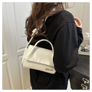Détail du sac en cuir blanc avec bandoulière à nœuds et logo métallique doré chic