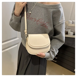 Detail view of cream saddle bag with smooth leather finish and adjustable shoulder strap