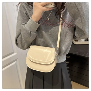 Detailed view of cream PU leather saddle bag with flap closure and adjustable strap