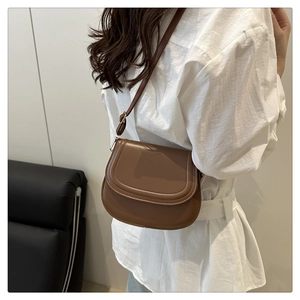 Detail of brown saddle crossbody bag in matte synthetic leather with adjustable strap
