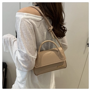 Détail du sac à main en similicuir beige montrant la bandoulière nouée et le logo doré