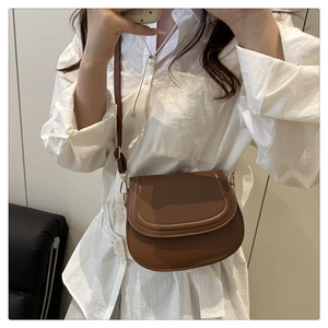 Mirror selfie showing the brown leather saddle bag with adjustable strap on white shirt