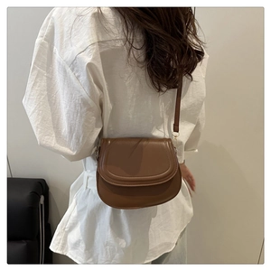 Detailed side view of a dark brown matte leather saddle bag with adjustable strap