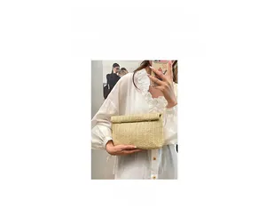 Detail of hand-woven straw envelope bag showing texture and versatile handheld strap