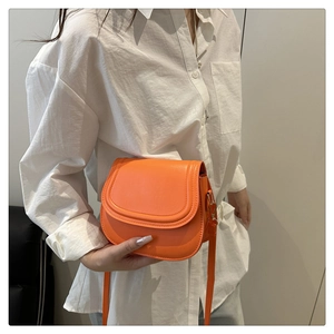 Detail of orange saddle bag showing matte leather texture and gold hardware buckle