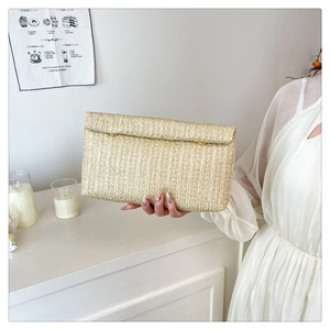 Detail of hand-held straw clutch bag with woven texture and envelope flap design