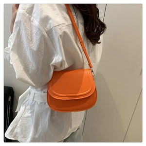 Detail of a bright orange saddle bag showing fine stitching and smooth leather texture