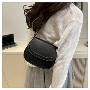 Detailed view of black saddle bag on shoulder showing stitching and texture
