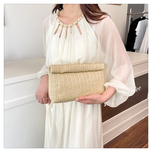 Detail of woven straw clutch with metal buckle clasp and natural texture finish