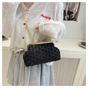 Detail of black rose texture fabric handbag with vintage gold clasp and chain strap