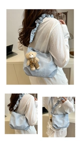 Detail of light blue nylon handbag featuring a pleated strap and plush bear charm