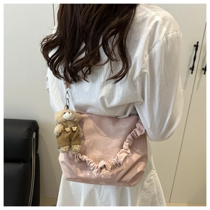 Detail of pink ruffled crossbody bag featuring a cute brown plush bear charm pendant