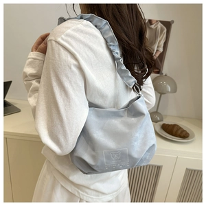 Detail of light blue pleated shoulder bag with Altumi logo in a lifestyle setting
