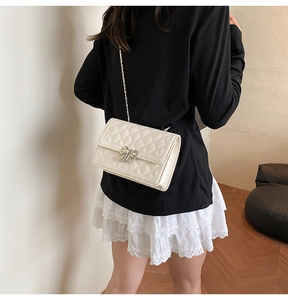 Gros plan d'un sac matelassé blanc avec boucle nœud argentée et bandoulière chaîne