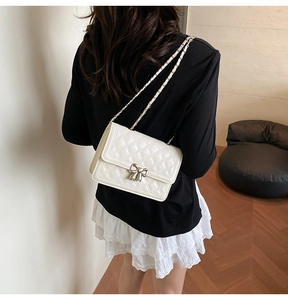 Détail du sac bandoulière blanc matelassé avec boucle nœud argentée et bandoulière