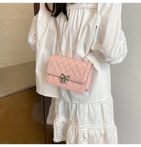 Détail du sac à bandoulière matelassé rose avec boucle nœud argent sur robe en dentelle