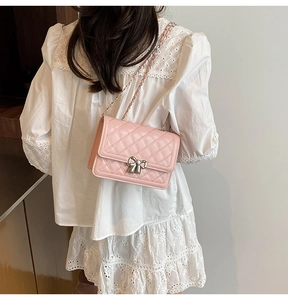 Détail du sac matelassé rose avec fermoir nœud argenté sur robe en dentelle