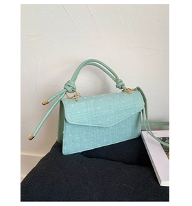 Detail of mint green textured fabric handbag with knotted handle and gold metal ring